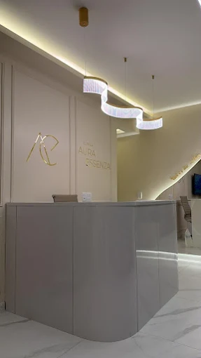 Recepção da Clínica Aura Essenza, com iluminação quente e a marca em dourado na parede